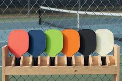 Solid pickleball paddles waiting in an open-play paddle rack, the usual queue for a shared court in Minnesota